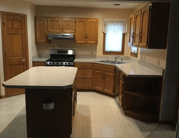 The same kitchen before refacing, with dark oak cabinet doors and a white laminate countertop