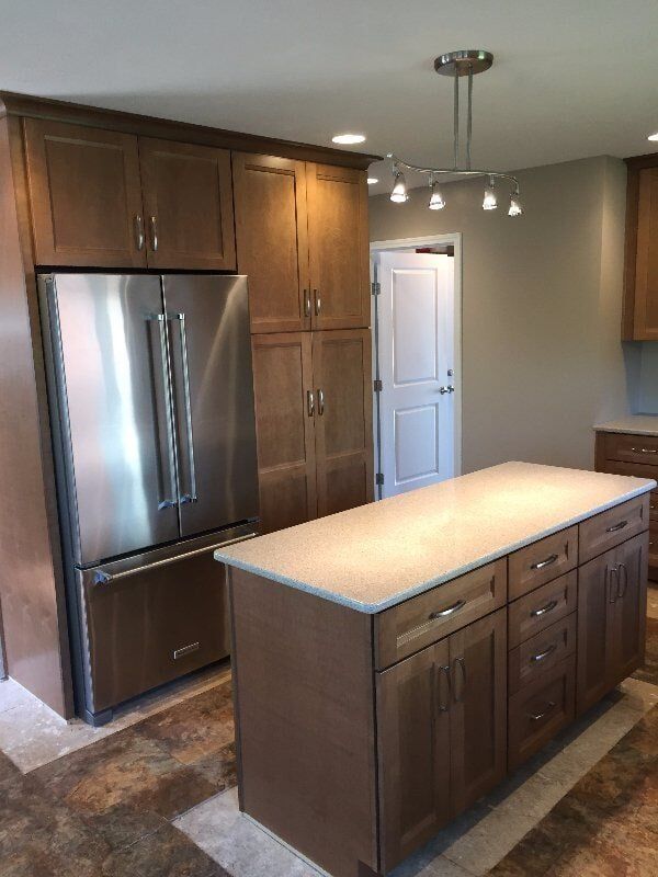 New stained cabinetry and a quartz-topped island installed by Pioneer Kitchens